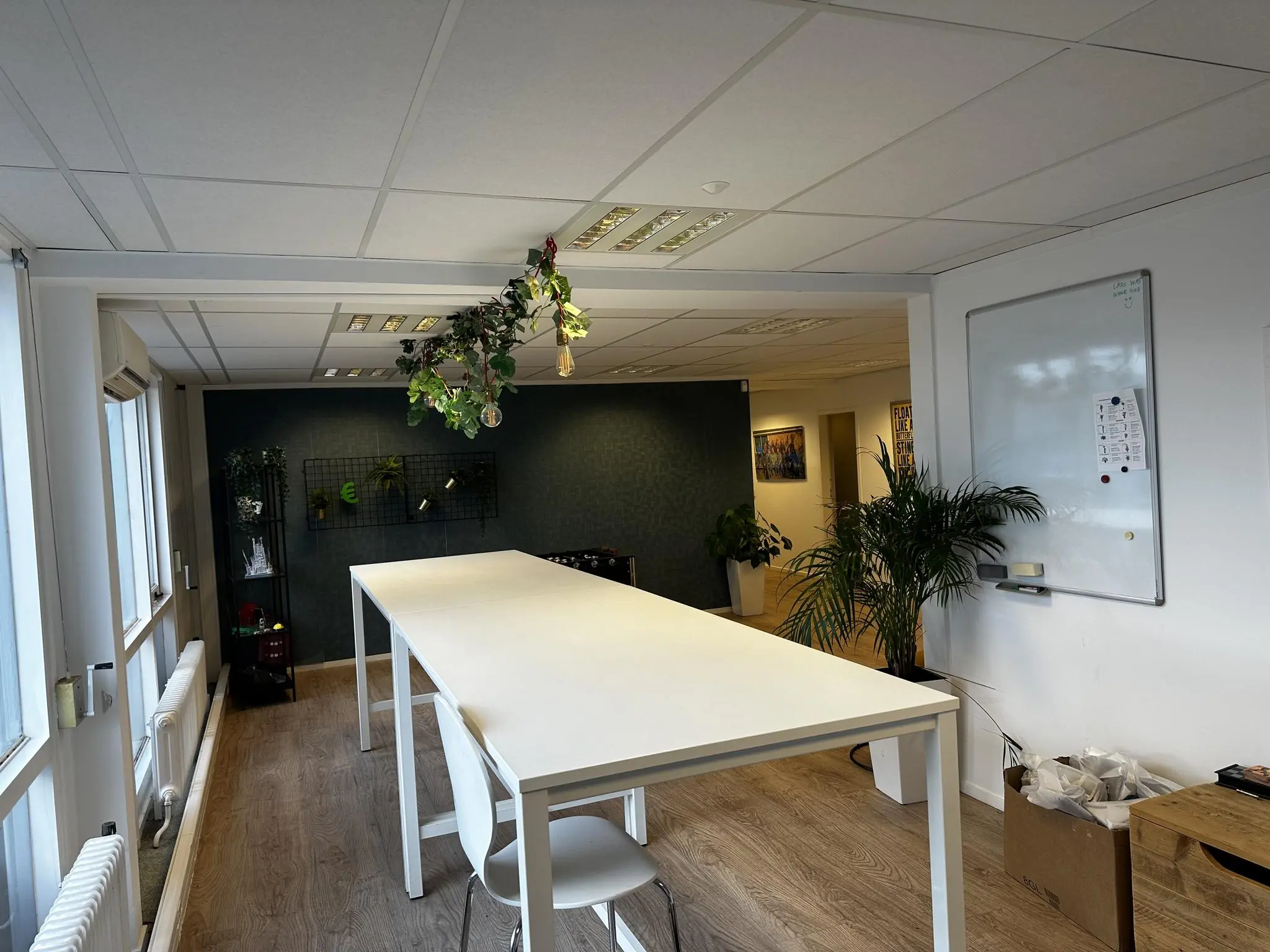 Moderne kantoorruimte aan de Koninginnegracht met hoge witte tafel, planten en een whiteboard aan de muur.