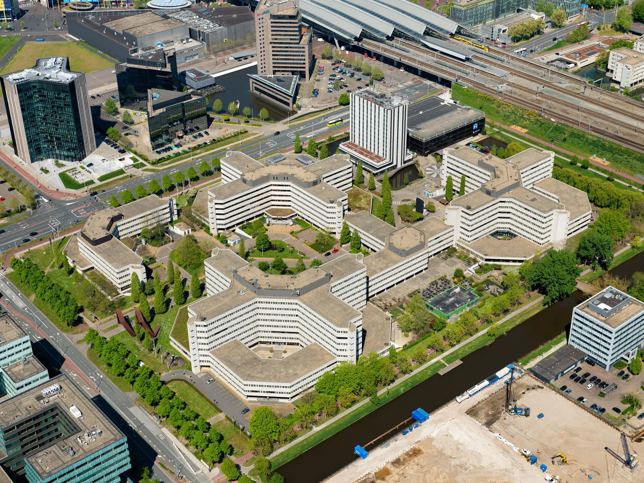 Luchtfoto van het kantoorgebouw Hoogoorddreef in Amsterdam-Zuidoost, omgeven door wegen, water en andere moderne gebouwen.