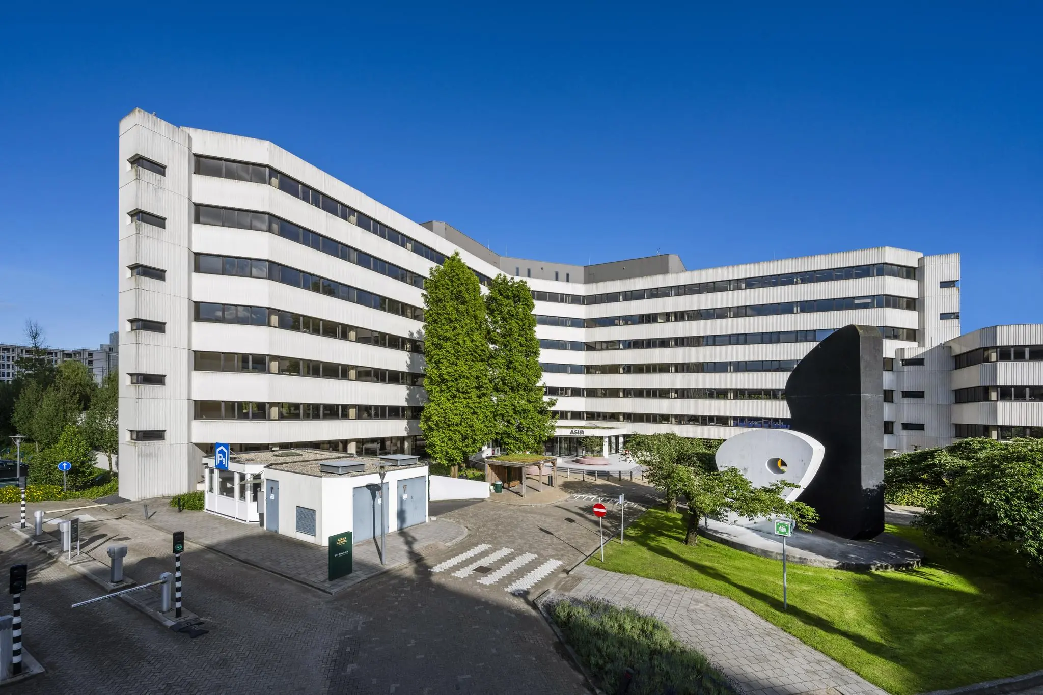 Kantoorgebouw aan de Hoogoorddreef in Amsterdam-Zuidoost met kunstobject en parkeervoorziening op de voorgrond.
