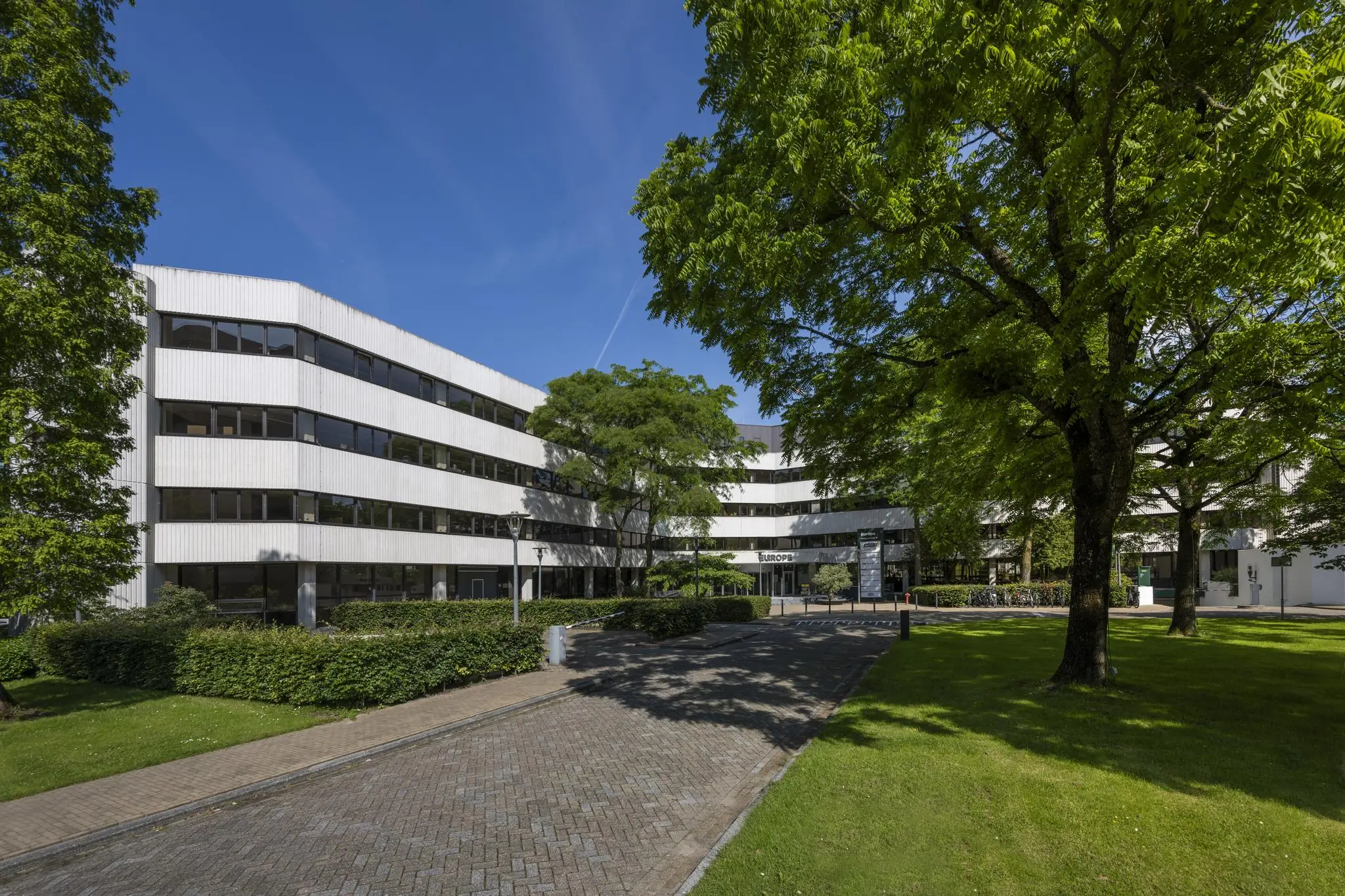 Kantoorgebouw Europa aan de Hoogoorddreef in Amsterdam, omgeven door groen en bomen op een zonnige dag.