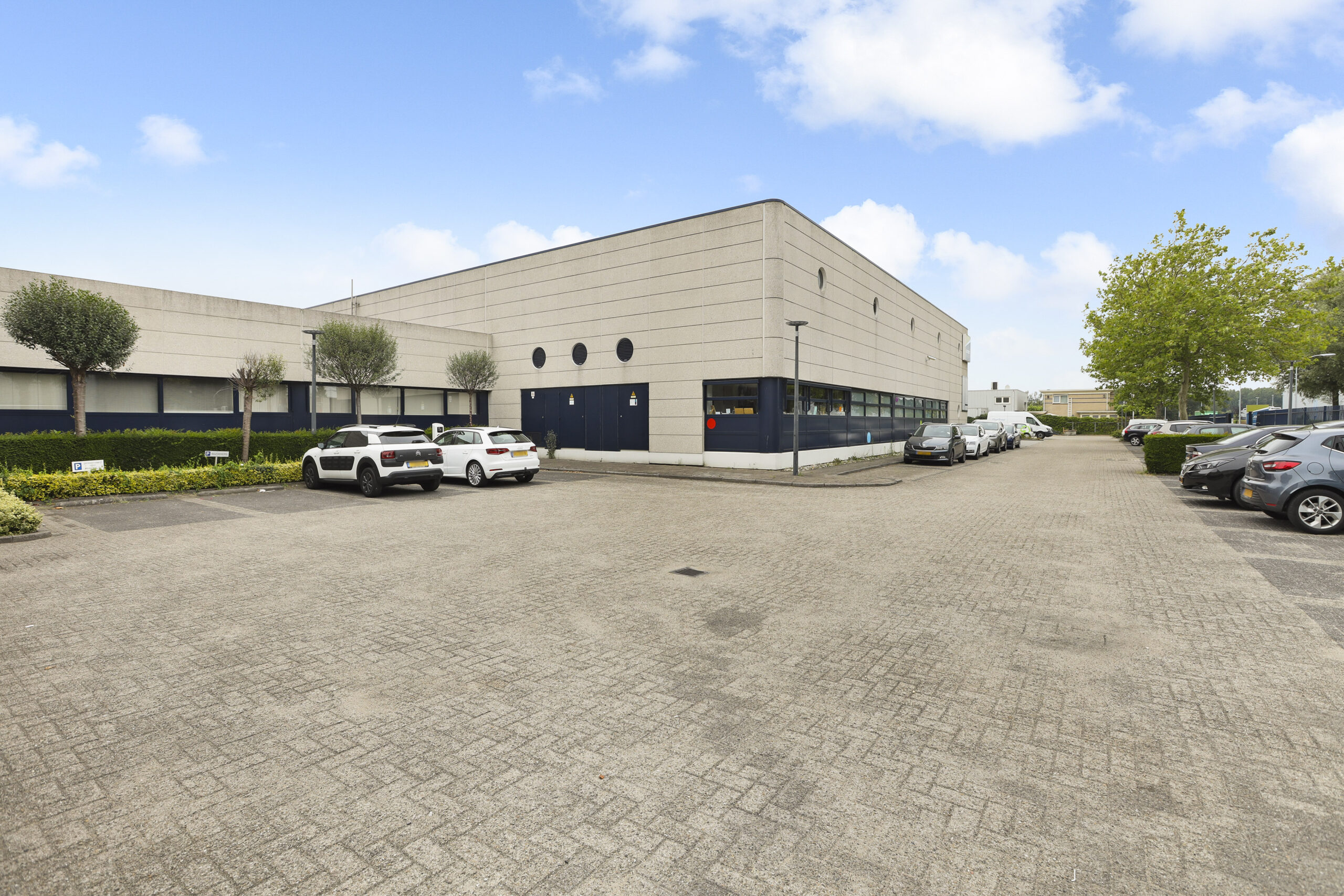 Buitenaanzicht van het Element Offices kantoorpand in Almere met parkeervakken en geparkeerde auto's.