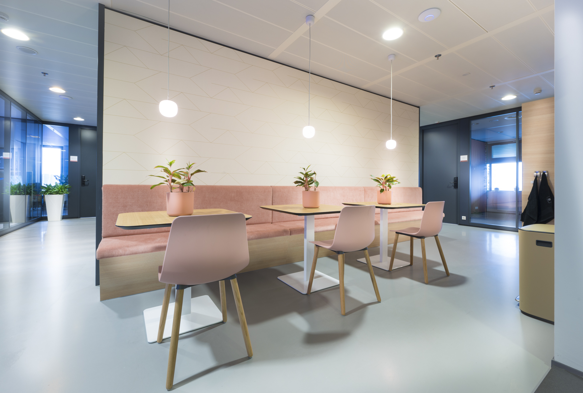 Een moderne zithoek in Scandinavische stijl met roze stoelen en tafels, versierd met planten.