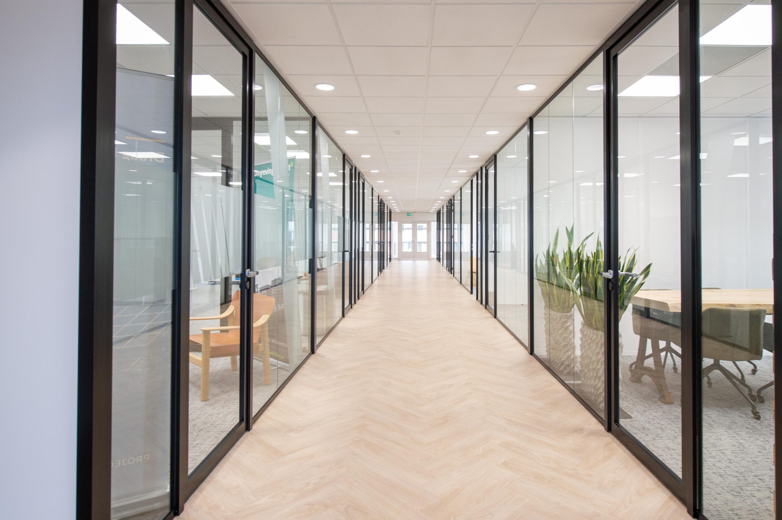 Een lange gang met glazen wanden en kantoorruimtes in het Rivium Quadrant gebouw.