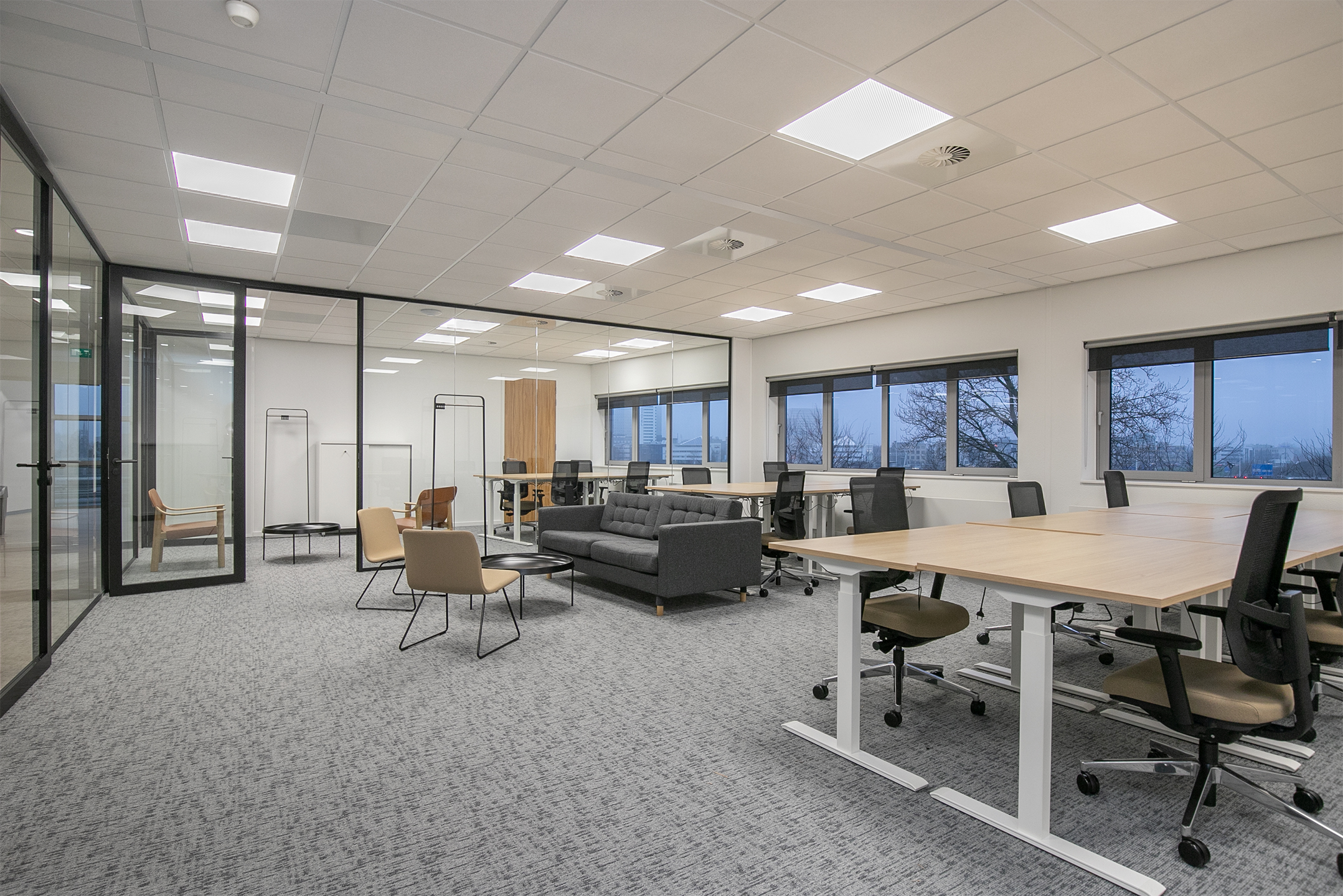 Een moderne, open kantoorruimte met bureaus, stoelen en glazen wanden in Rivium Quadrant.