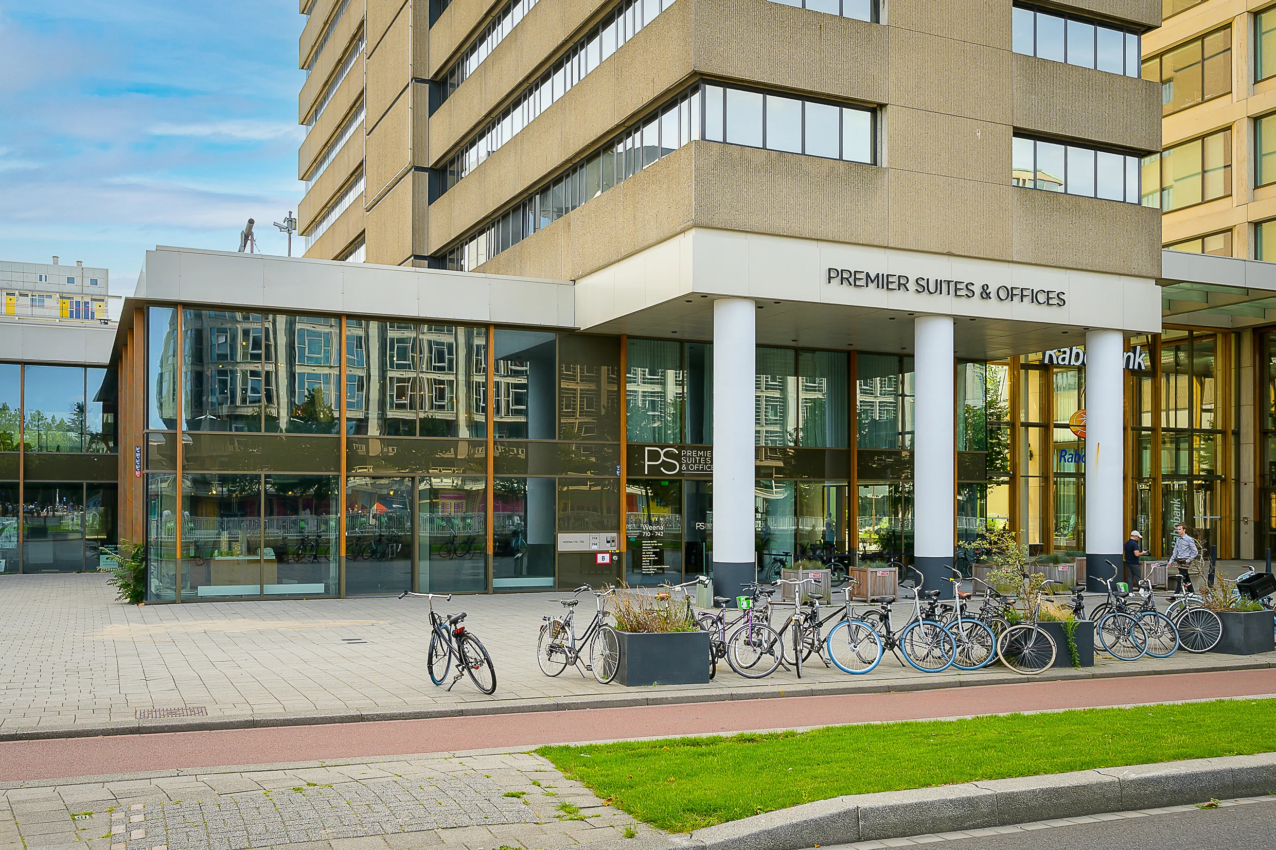 Entrance of the Premier Suites & Offices building on Weena street with parked bicycles and large glass windows.