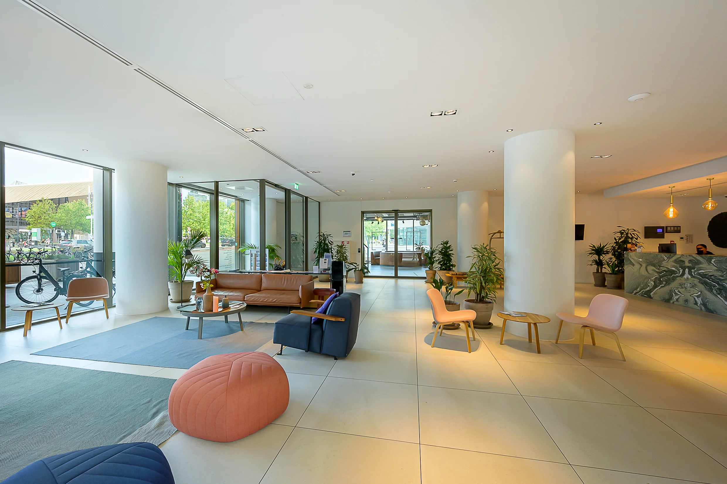 Modern hotel lobby at Weena 210 with contemporary furniture, indoor plants, and a reception desk.