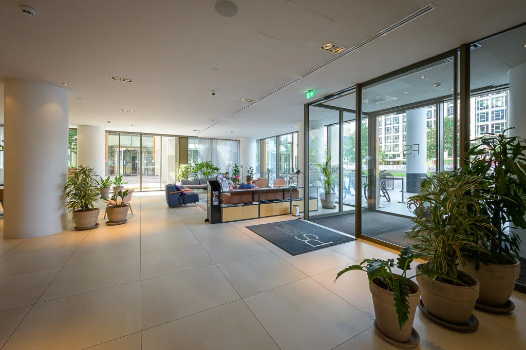 Modern office lobby at Weena 210, featuring large windows, indoor plants, and seating areas.