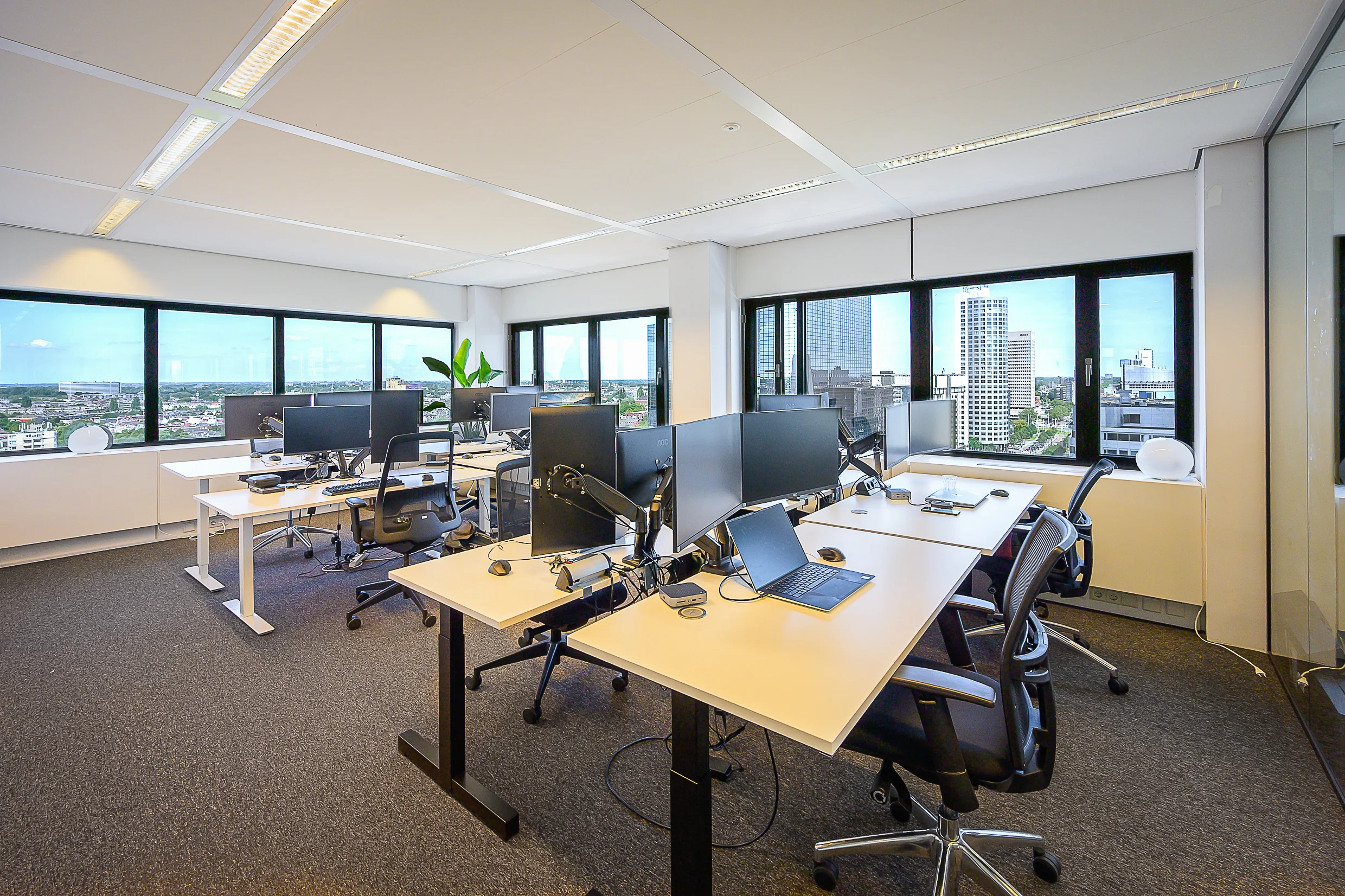 Modern office space with multiple workstations and a city view from Weena, Rotterdam.