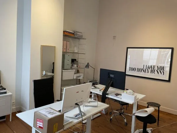 Moderne kantoorruimte met bureaus, computers, een opbergkast en een grote ingelijste poster met de tekst "I love you too honey bunny".