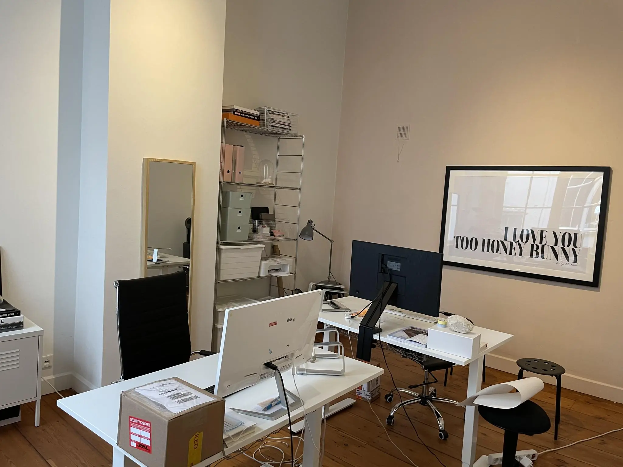 Moderne kantoorruimte met bureaus, computers, een opbergkast en een grote ingelijste poster met de tekst "I love you too honey bunny".