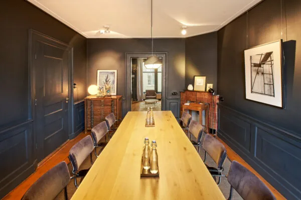 Stijlvol vergaderruimte aan de Singel met een lange houten tafel, kunst aan de muren en een warme, moderne inrichting.