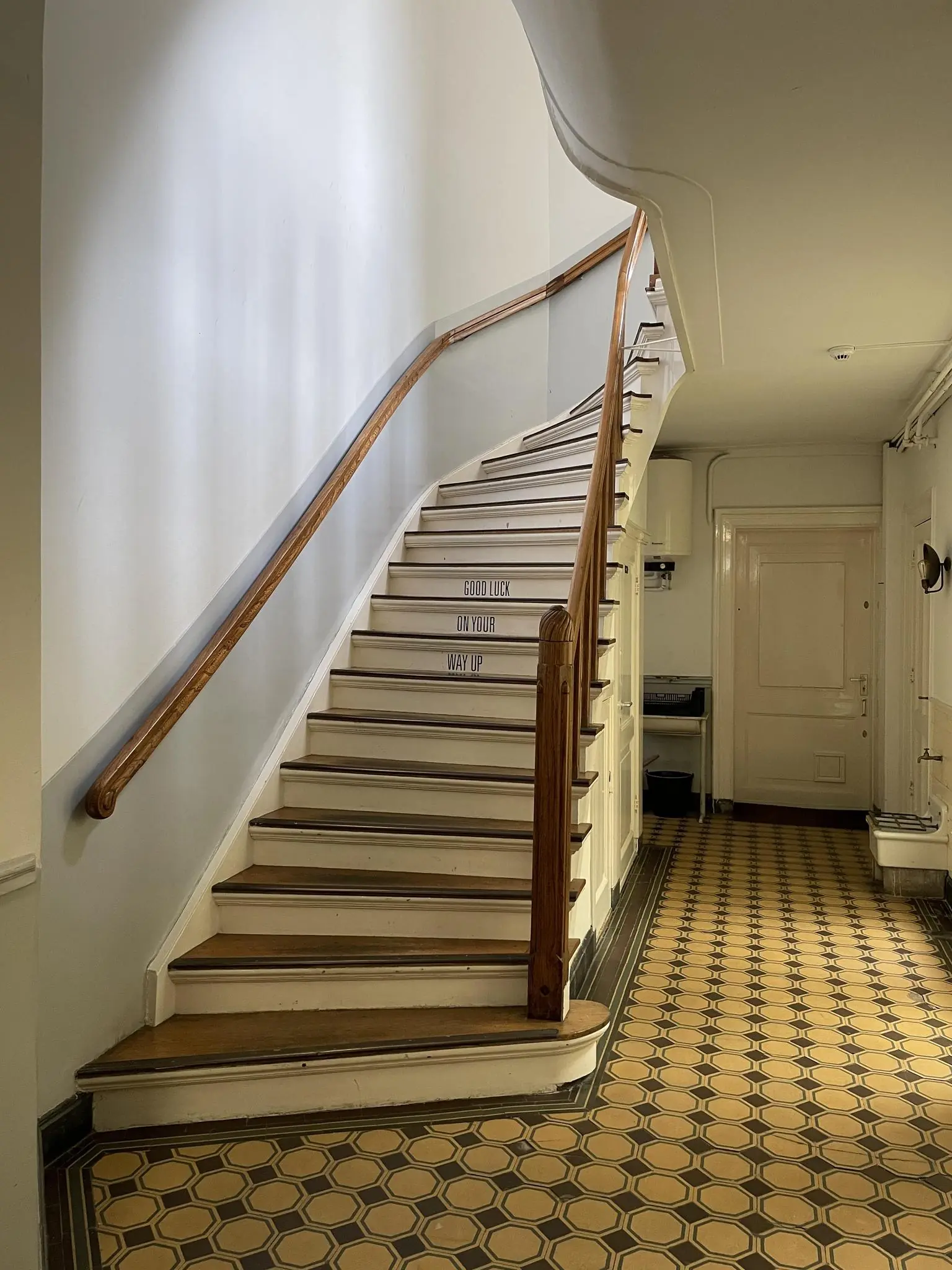 Trapopgang met houten leuning en betegelde vloer in een historisch gebouw aan de Singel.