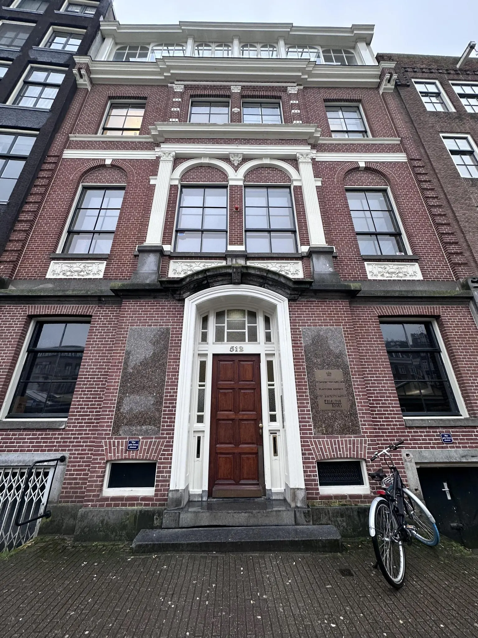 Voorgevel van een historisch pand aan de Singel in Amsterdam met huisnummer 512 en een fiets voor de deur.