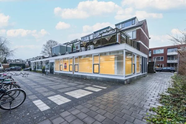 Straatzicht van de Wallesteinlaan met een modern hoekpand met grote ramen en fietsenstalling.