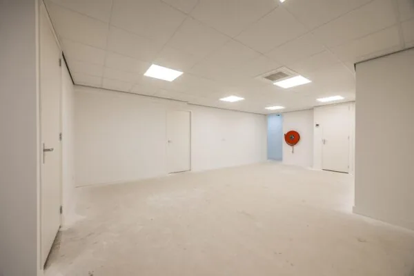 Lege, wit afgewerkte ruimte aan de Wallesteinlaan met systeemplafond, meerdere deuren en een oranje brandslanghaspel aan de muur.