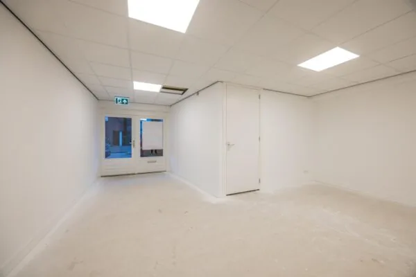 Leeg wit commercieel interieur aan de Wallesteinlaan met systeemplafond en glazen toegangsdeur.
