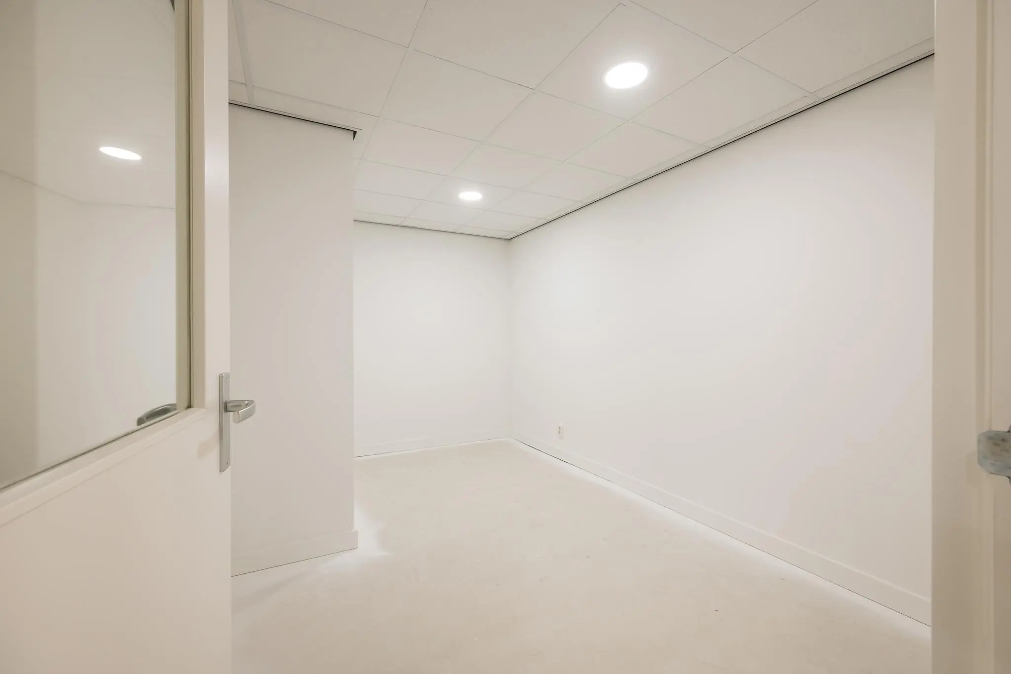 Lege, witte kamer aan de Wallesteinlaan met systeemplafond en ingebouwde plafondverlichting.
