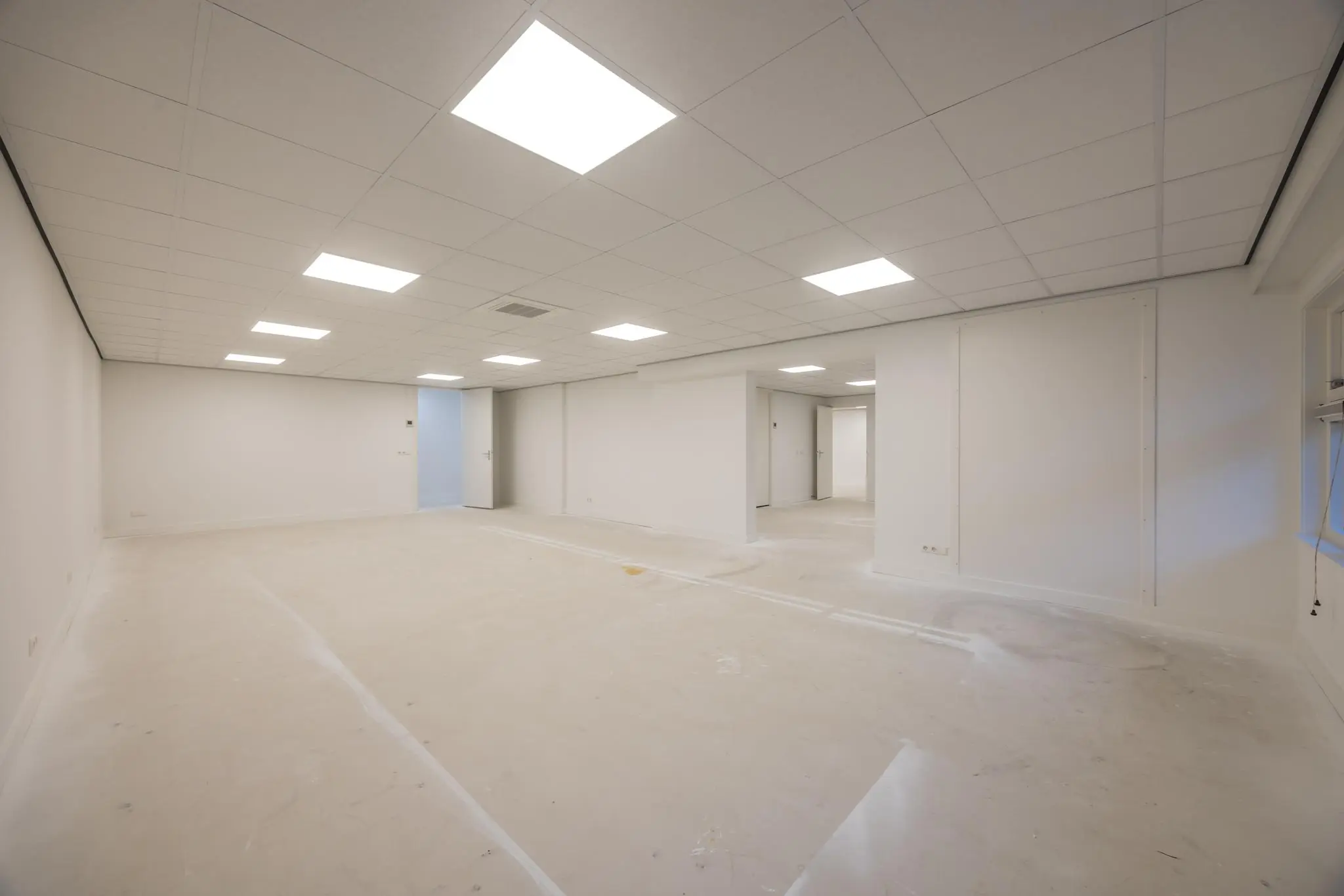 Lege, witgeschilderde kantoorruimte aan de Wallesteinlaan met systeemplafond en tl-verlichting.