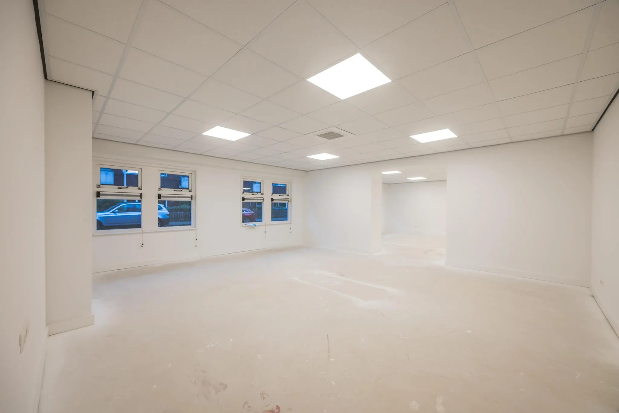 Lichte, lege ruimte aan de Wallesteinlaan met systeemplafond en meerdere ramen aan de straatzijde.