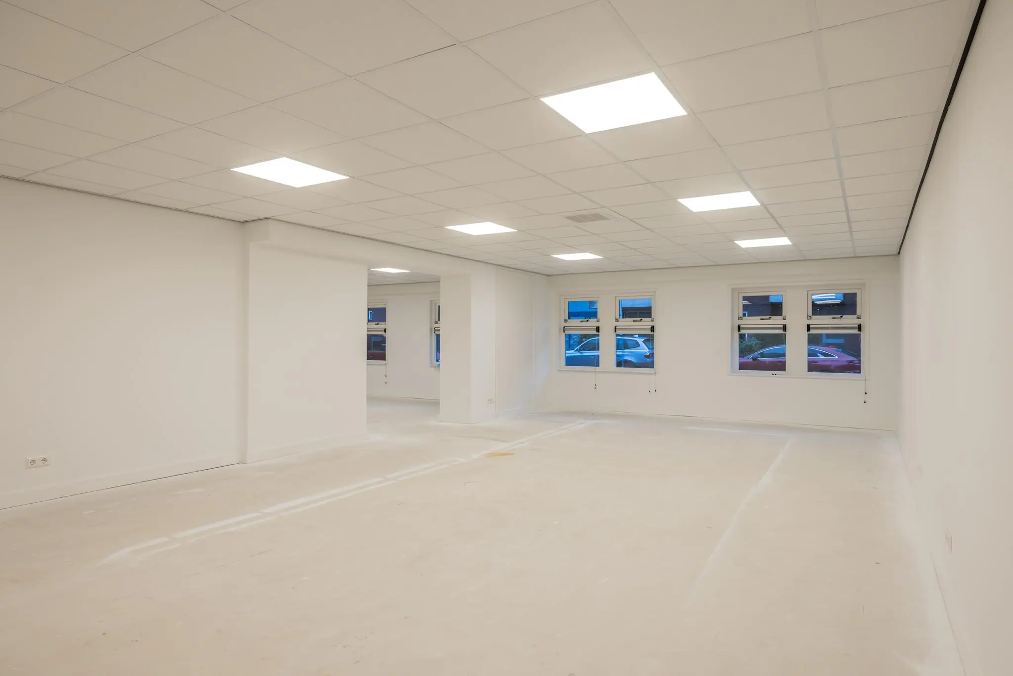 Leeg, wit afgewerkt kantoor- of bedrijfsruimte aan de Wallesteinlaan met systeemplafond en meerdere ramen.