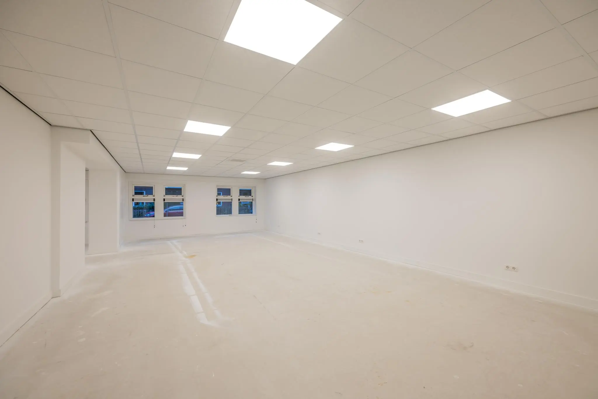 Leeg, wit afgewerkt kantoorpand aan de Wallesteinlaan met systeemplafond en tl-verlichting.