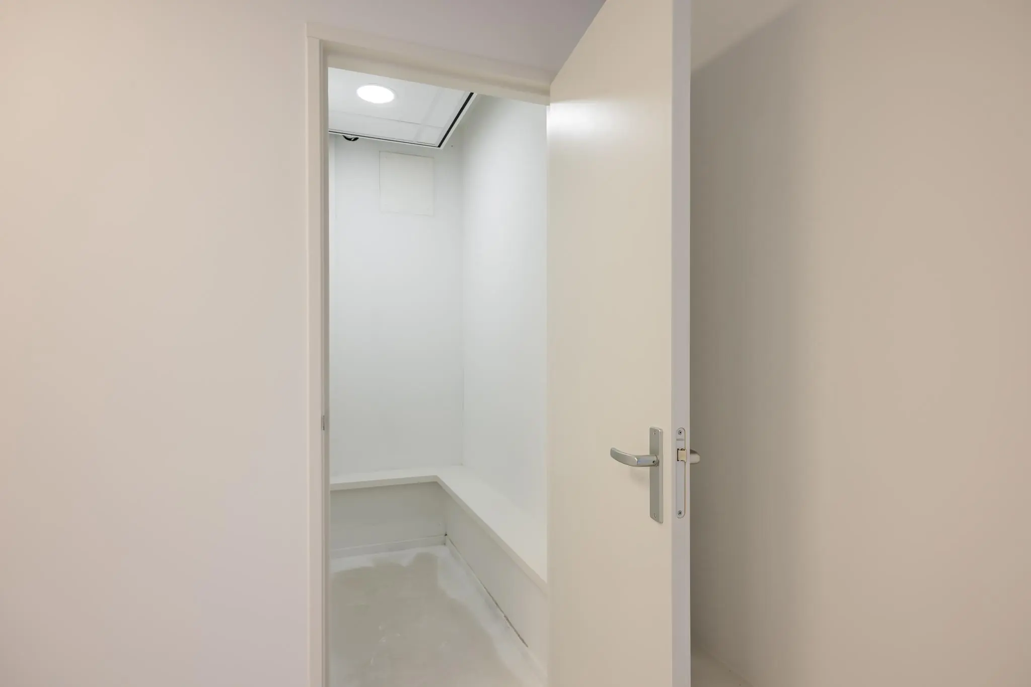 Witte deur geopend naar kleine, lege berging met ingebouwde plank aan de Wallesteinlaan.