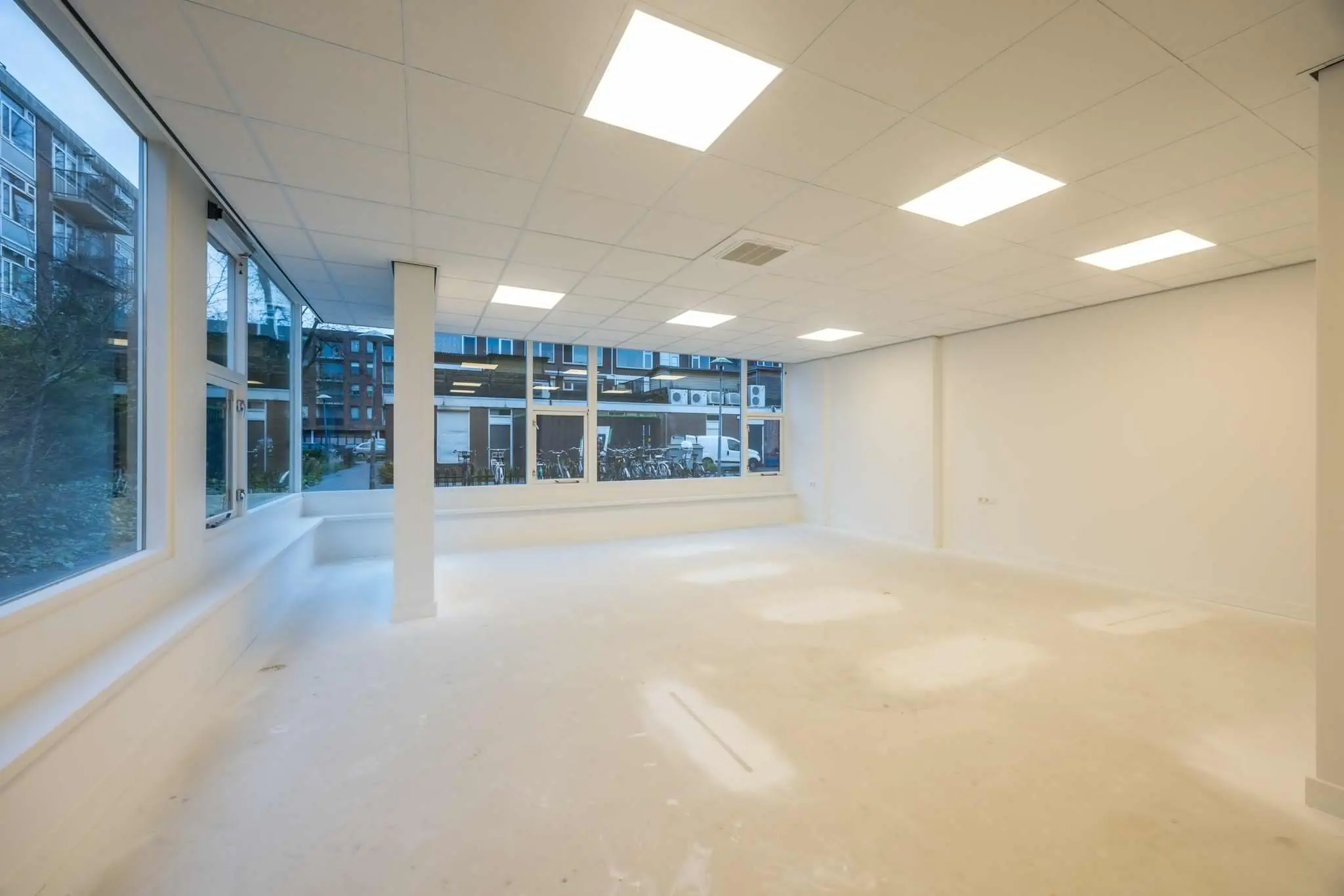 Lichte, lege kantoorruimte aan de Wallesteinlaan met grote ramen en een systeemplafond met inbouwverlichting.