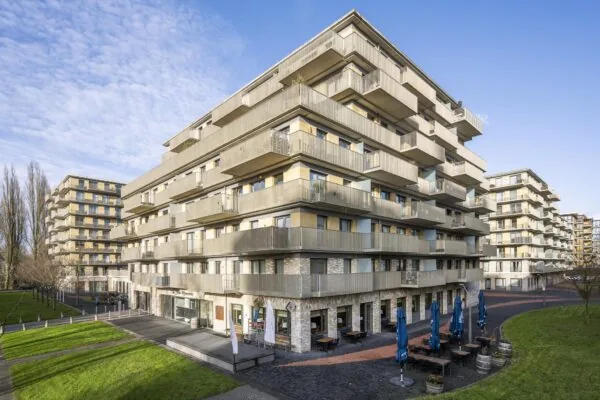 Moderne appartementencomplexen aan de Laan van de Helende Meesters met terrassen, groenstroken en horeca op de begane grond.