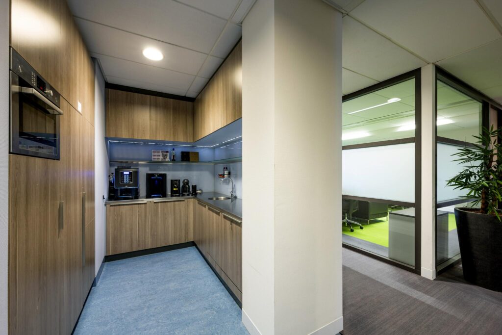 Kleine moderne pantry met koffieapparaten en ingebouwde keukenkasten in een kantoor aan de Laan van de Helende Meesters.