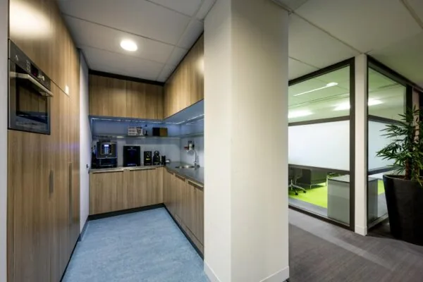 Kleine moderne pantry met koffieapparaten en ingebouwde keukenkasten in een kantoor aan de Laan van de Helende Meesters.