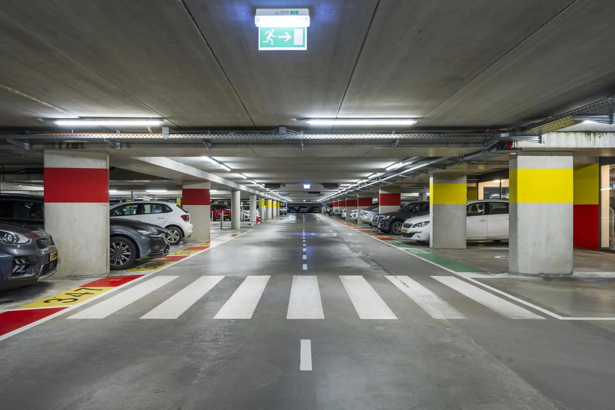 Ondergrondse parkeergarage aan de Laan van de Helende Meesters met gemarkeerde parkeerplaatsen en voetgangerspad.
