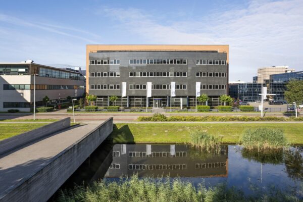 Kantoorgebouw aan de Paasheuvelweg met moderne gevel en weerspiegeling in het water op de voorgrond.