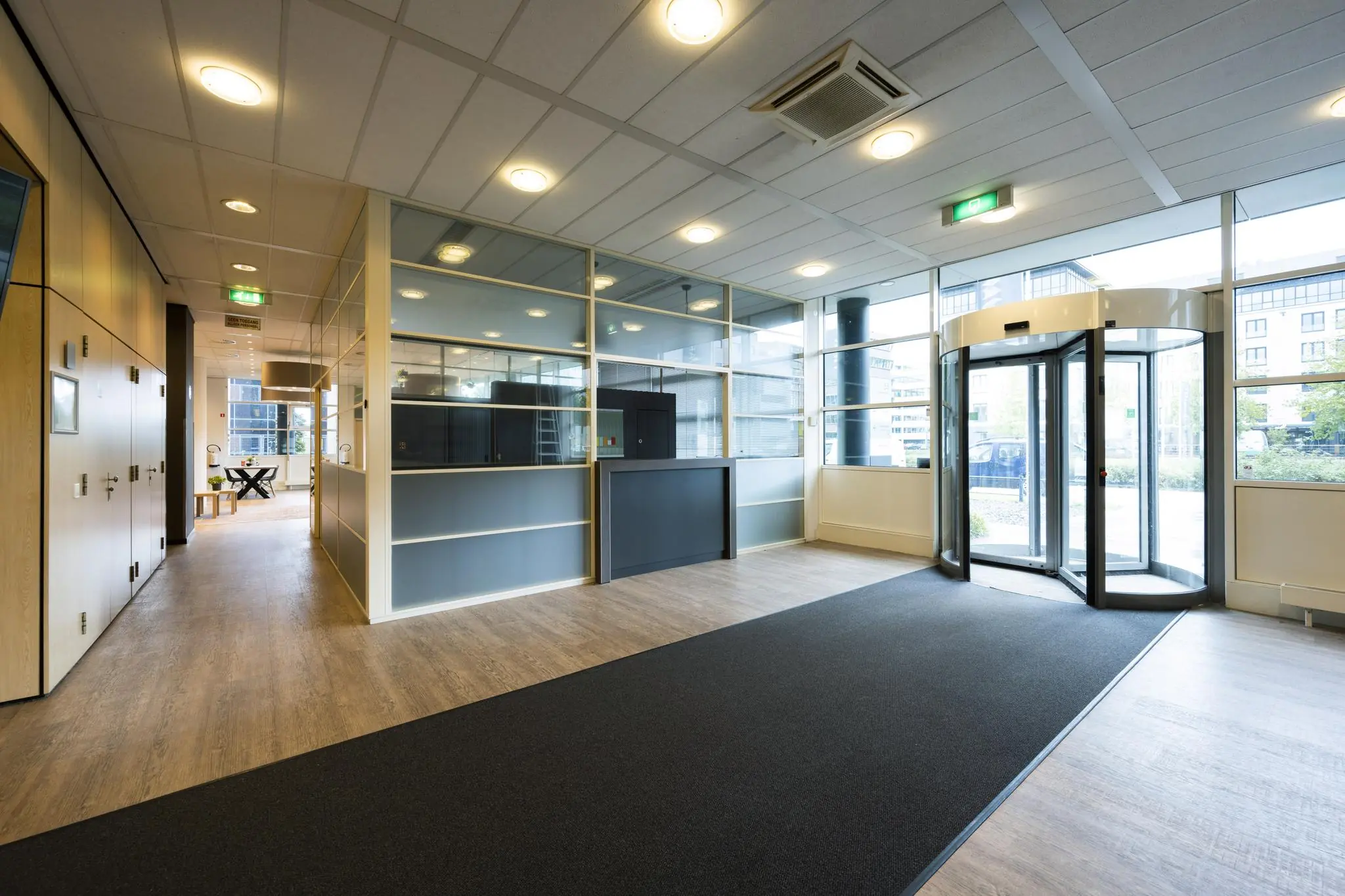 Moderne entreehal van een kantoorgebouw aan de Paasheuvelweg met glazen draaideur en balie.