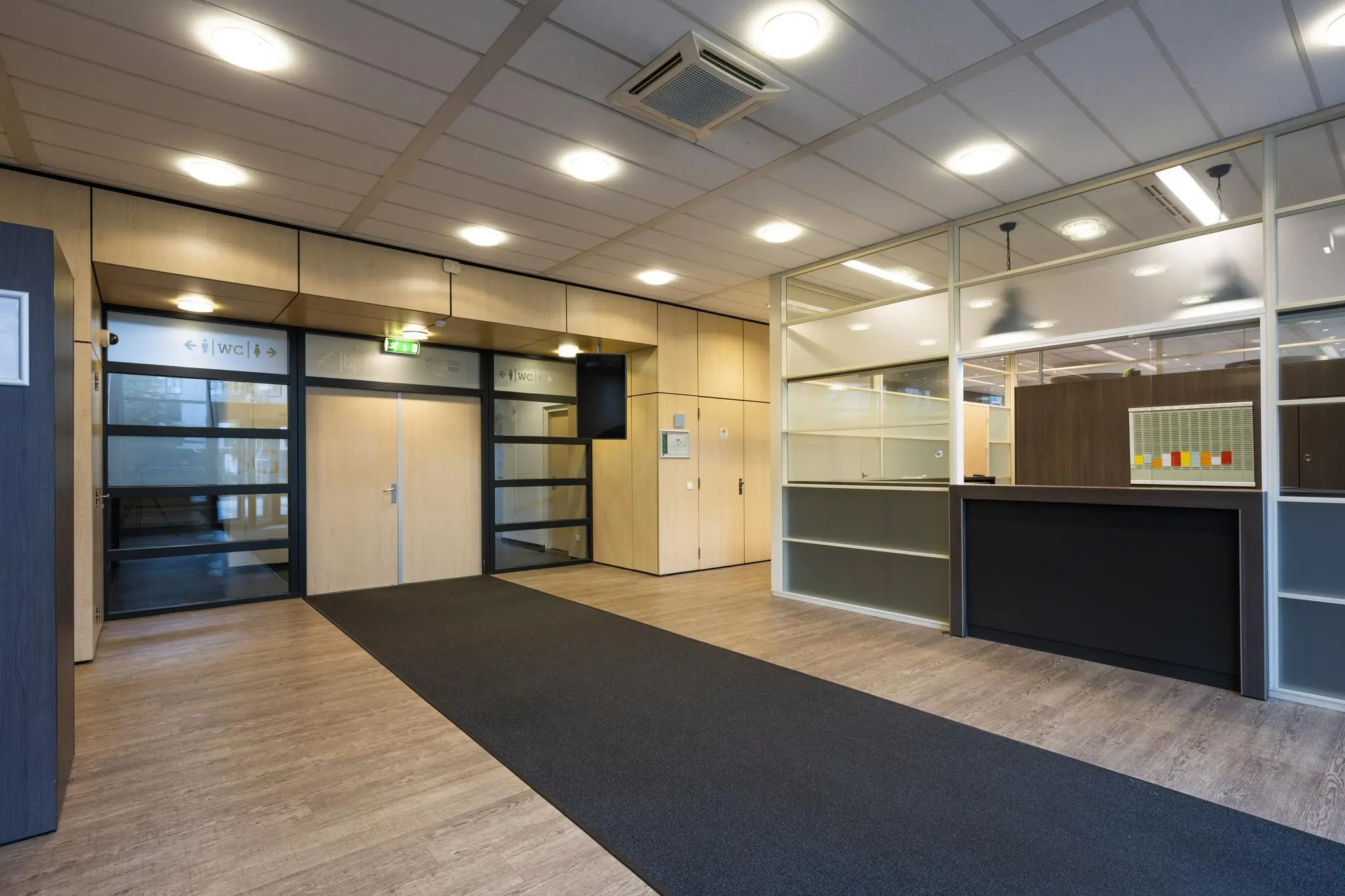 Moderne entreehal van een kantoorpand aan de Paasheuvelweg met receptiebalie en duidelijke bewegwijzering naar de toiletten.