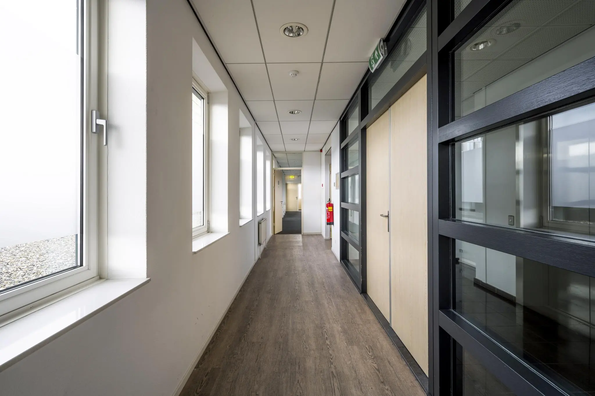 Licht en modern kantoorpand interieur met glazen wanden en houten vloer aan de Paasheuvelweg.