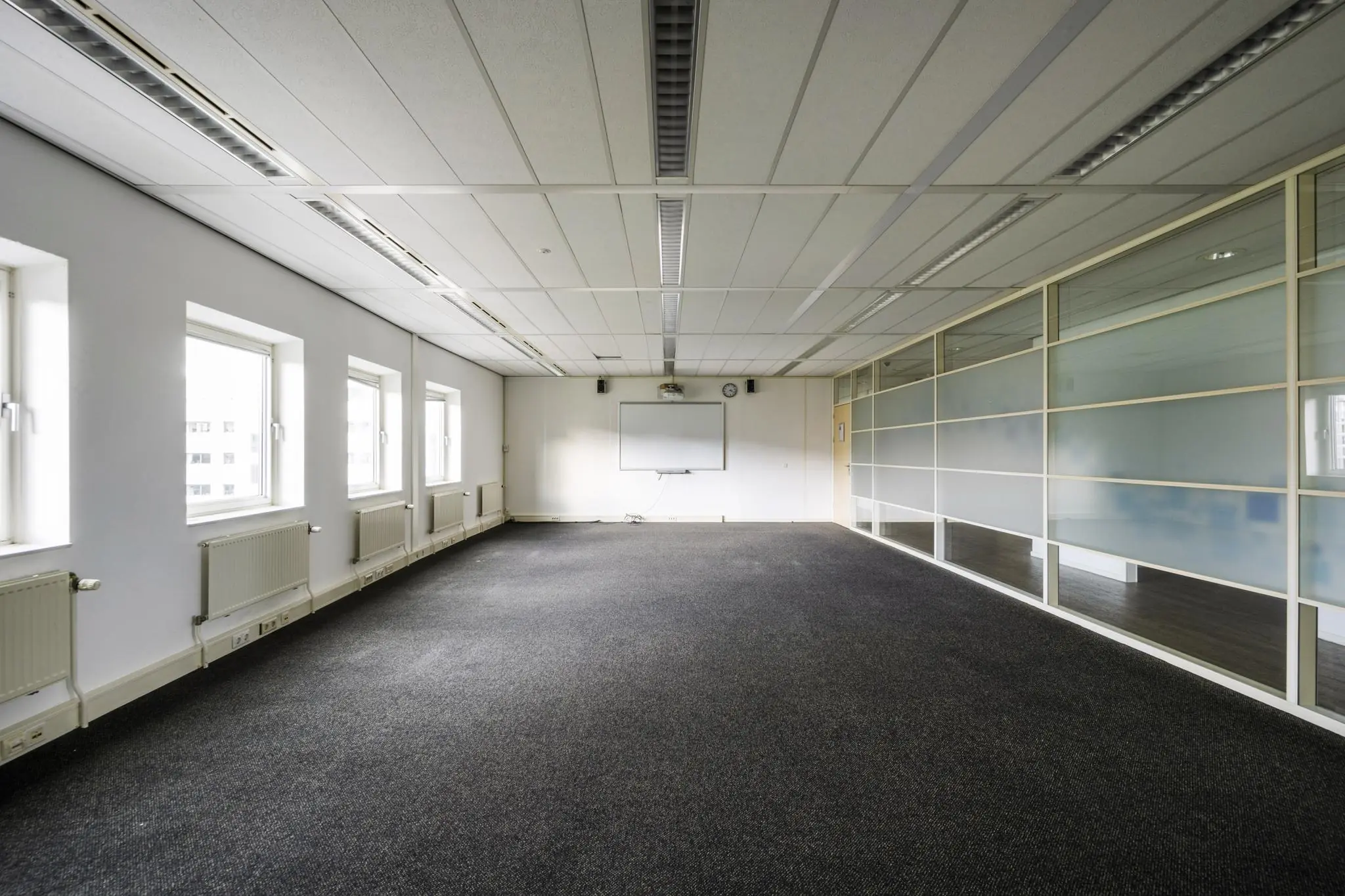 Leeg kantoorruimte aan de Paasheuvelweg met grote ramen, glazen scheidingswand en een whiteboard aan de muur.