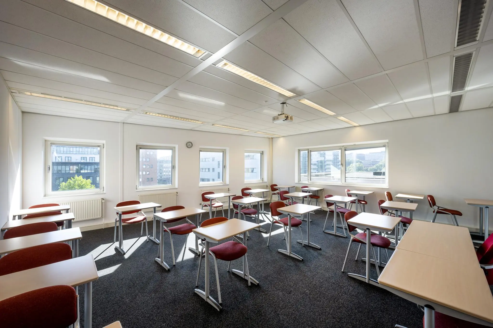 Lichte, moderne lesruimte aan de Paasheuvelweg met losse tafels, rode stoelen en uitzicht op kantoorgebouwen.