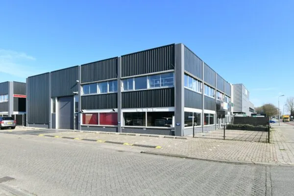 Modern bedrijfspand aan de Zonnebaan met zwart stalen gevelbekleding op een zonnige dag.
