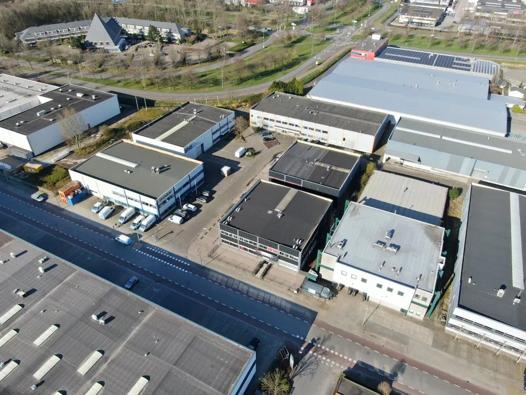 Luchtfoto van een bedrijventerrein aan de Zonnebaan in Utrecht met diverse bedrijfsgebouwen en geparkeerde voertuigen.