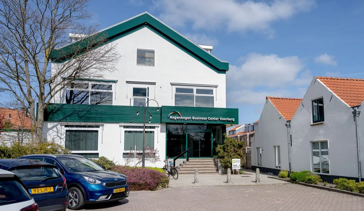 Vooraanzicht van het Regenbogen Business Center Voorburg aan het Oosteinde, met geparkeerde auto's en een fiets voor de ingang.