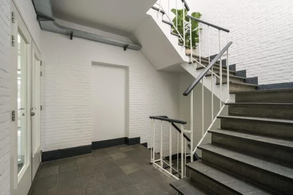 Trappenhuis met witte bakstenen muren, zwarte stenen treden en een plant op de overloop aan de Mercuriusweg.