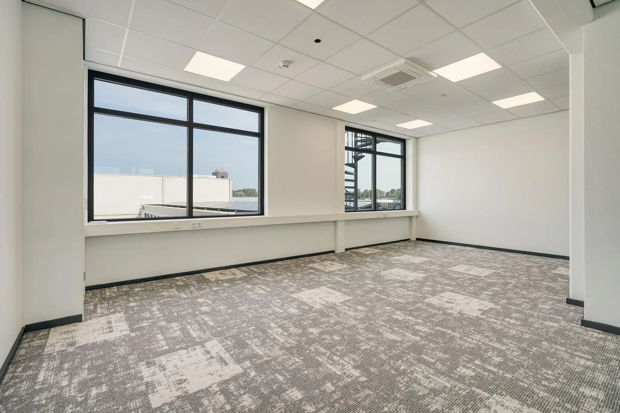 Licht en modern leeg kantoor op de Mercuriusweg met grote ramen en grijs tapijt.