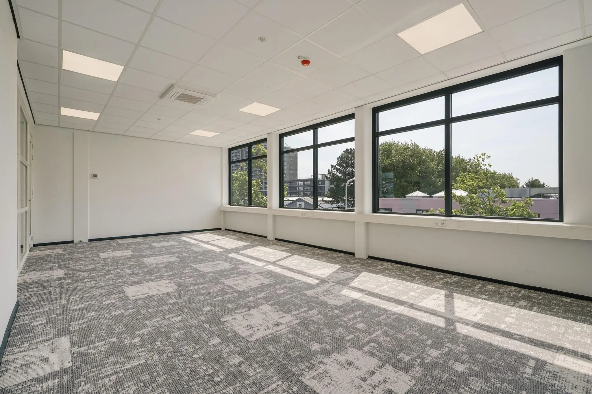 Licht en modern kantoorpand aan de Mercuriusweg met grote ramen en grijze tapijtvloer.