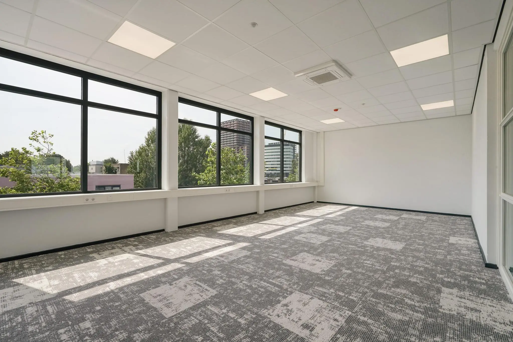Licht en modern kantoorpand aan de Mercuriusweg met grote ramen en grijs tapijt.