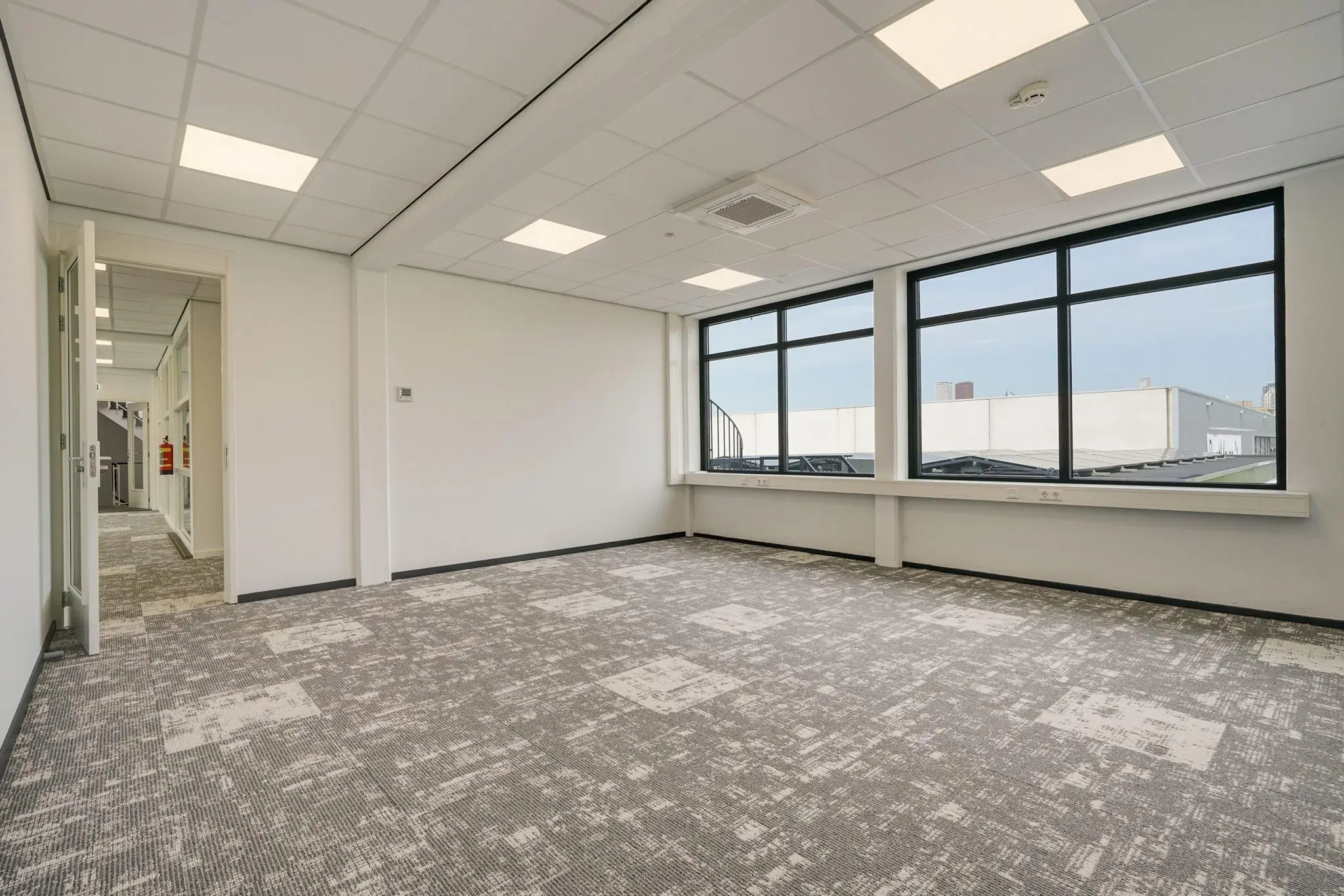 Lichte, lege kantoorruimte aan de Mercuriusweg met grote ramen en modern tapijt.