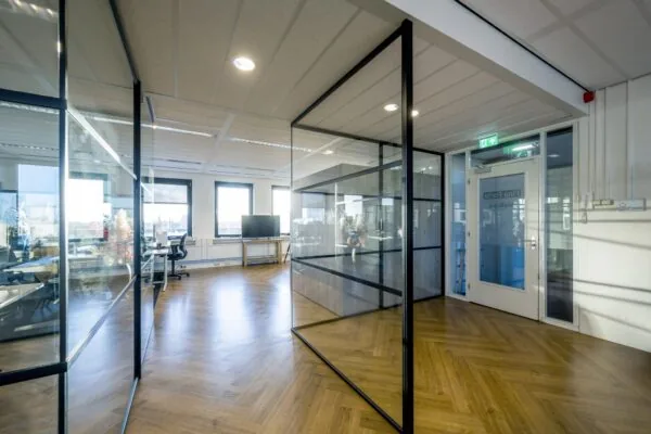 Moderne kantoorruimte op Radarweg met glazen wanden, houten visgraatvloer en veel natuurlijk licht.