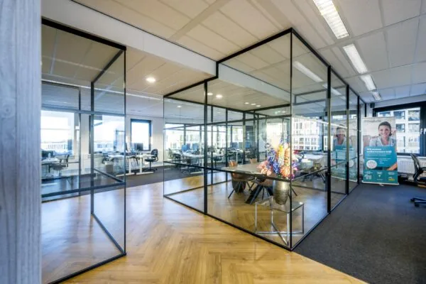 Modern kantoorinterieur aan de Radarweg met glazen vergaderruimte, bloemen op tafel en Finaforte-promotiemateriaal.