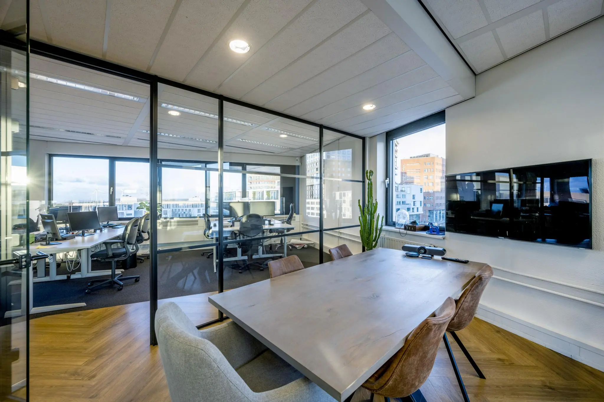 Moderne vergaderruimte met houten tafel, glazen wanden en uitzicht op kantoorruimte aan de Radarweg.