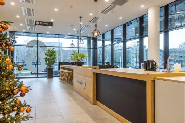 Moderne ontvangsthal aan de Winthontlaan met een kerstboom, receptiebalie en grote glazen ramen.