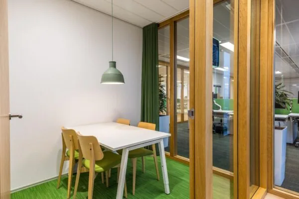 Moderne vergaderruimte aan de Winthontlaan met een witte tafel, vier houten stoelen en groen accentinterieur.